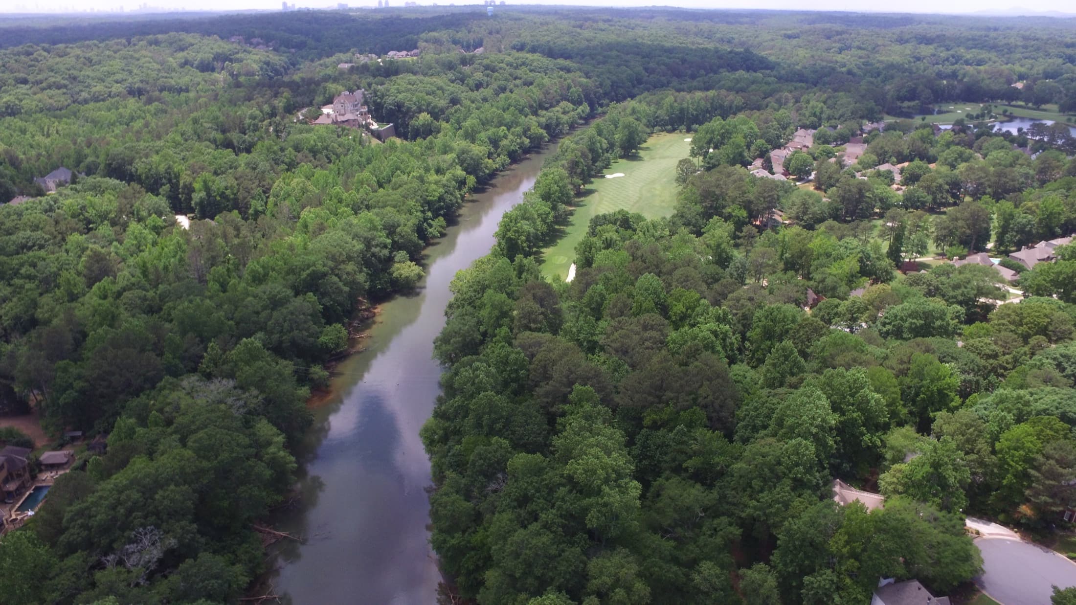 Aerial view of a river running beside trees and a fairway