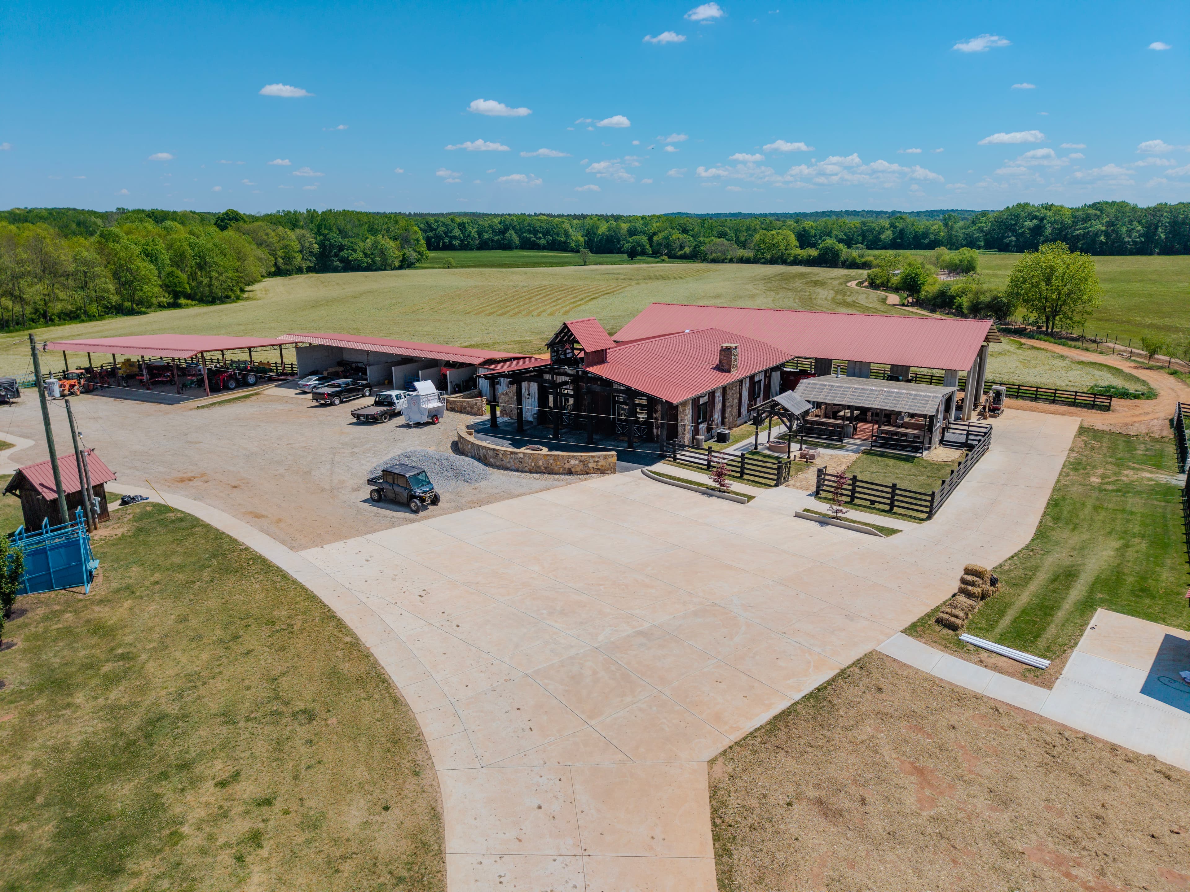 Wide aerial view of a rural property with red-roof buildings and open fields